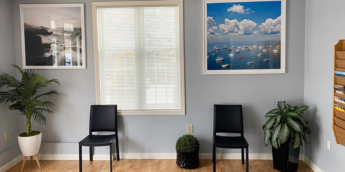 office reception area with black chairs and nautical pictures on wall