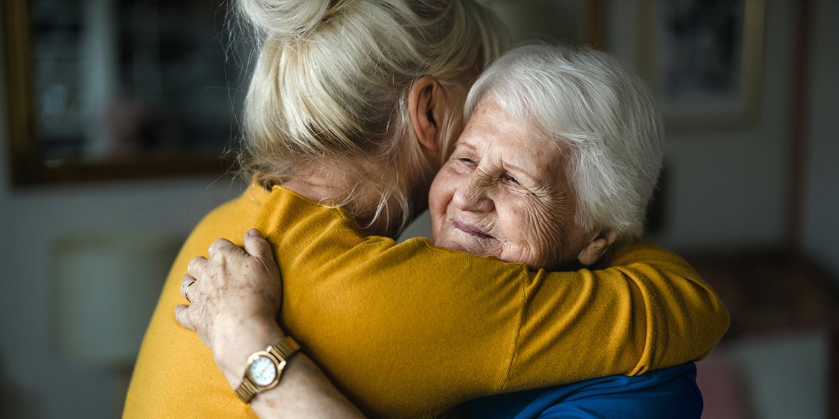 senior woman and caretaker hugging